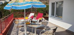a table and chairs under an umbrella on a balcony at Apartament Panorama - BastetBS in Sveti Vlas