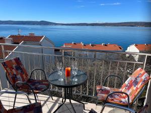 a table and chairs on a balcony with a view of the water at Apartman Maja in Selce