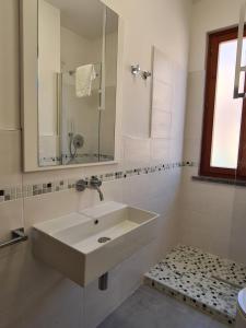 a white bathroom with a sink and a mirror at Villaggio Mietta in Castiglioncello