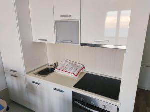 a kitchen with white cabinets and a sink at Sea view & pool studio by Pag tours in Pag +3 photos