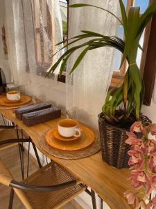 a wooden table with two cups of coffee and a potted plant at Quinta São Miguel in Santo Antônio do Pinhal