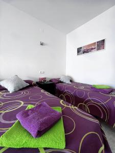 1 Schlafzimmer mit 2 Betten mit lila und grünen Decken in der Unterkunft Salou quiet side Apartments in Salou