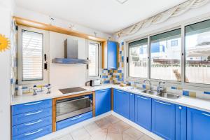 una cocina con armarios azules y ventanas en Villa Elliana by Ezoria Villas, en Protaras