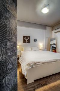1 dormitorio con cama blanca y pared en Beautiful and cozy studio next to Athens center, en Atenas