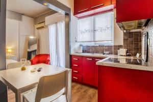 una pequeña cocina con armarios rojos y una mesa blanca en Beautiful and cozy studio next to Athens center, en Atenas