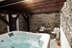 a bath tub in a room with a stone wall at Hazai Provence in Kapolcs