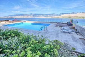 a swimming pool next to a body of water at Sea view & pool studio by Pag tours in Pag