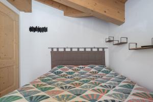 ein Schlafzimmer mit einem Bett mit einer bunten Decke in der Unterkunft DolomiApartments - Appartamento Coronelle in Predazzo