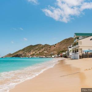 a sandy beach with houses and the ocean at Deux pièces sur la belle plage de Grand Case in Grand Case