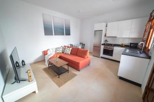 a living room with an orange couch and a kitchen at Casa Carmen in Haría