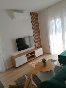 Una sala de estar con un televisor, un sofá y una mesa. en Apartments Jakov, en Makarska