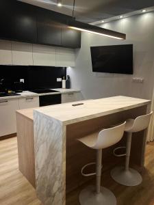 a kitchen with a counter and two stools in it at AMSTERDAM - nowy apartament w centrum z prywatnym zadaszonym parkingiem in Nowy Targ