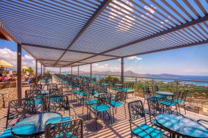 eine Terrasse mit Tischen und Stühlen und Meerblick in der Unterkunft Elounda Water Park Residence Hotel in Elounda