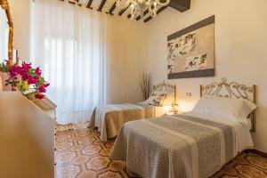een slaapkamer met 2 bedden en een raam bij Appartamenti Panoramici Piazza delle Erbe in San Gimignano
