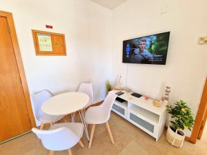 Pokój ze stołem i krzesłami oraz telewizorem na ścianie w obiekcie ZARCO - Apartment in Vilamoura with 2 Pools near the Beach & the Marina w mieście Quarteira