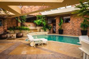 a swimming pool with a patio furniture and a brick wall at Villa Los Lagos in Bogotá