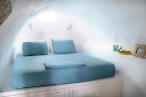 a bedroom with a blue bed in a white room at Castro House in Pera Gyalos