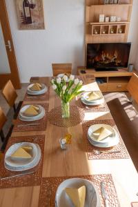 Ferienwohnung Hertreiter in Dingolfing 110qm في دينغولفينغ: طاولة غرفة الطعام مع الأطباق والزهور عليها