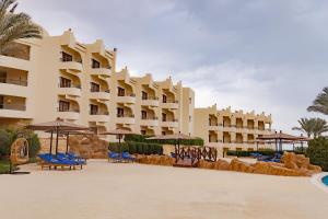 duży hotel z krzesłami i parasolami przed nim w obiekcie Life Resorts Coral Hills Beach & SPA w mieście Al-Kusajr