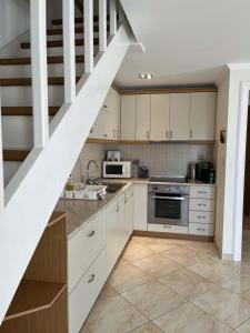 a kitchen with white cabinets and a spiral staircase at Villa Ampelaki "30 meters to beach" in Paleokastritsa