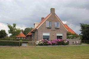 une grande maison avec des fleurs dans la cour dans l'établissement Ballumerhoeve Skip lodge, à Ballum