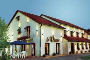 a white building with tables and chairs in front of it at Hotel La Venerie in Virton