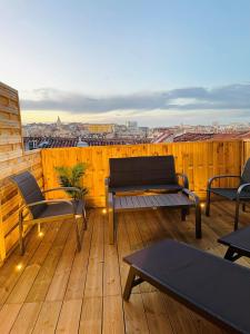 einen Balkon mit Stühlen und Tischen auf einer Holzterrasse in der Unterkunft Honoré - Rooftop- Centre Vieux Port in Marseille