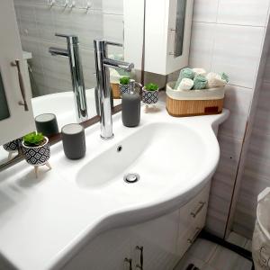 bagno con lavandino bianco e specchio di Ξενώνας Vasiliki a Vathí