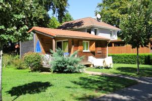 a small house with a porch and two chairs in the yard at L’Orée du Bois by Noricamp in Arthez-de-Béarn