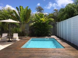 a swimming pool on a wooden deck with an umbrella at Villa avec piscine privée in Saint-François