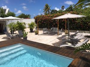 a swimming pool with chairs and umbrellas next to a patio at Villa avec piscine privée in Saint-François