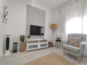 salon z telewizorem i krzesłem w obiekcie Covadonga Suite Home w Sewilli