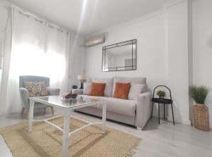 salon z białą kanapą i stołem w obiekcie Covadonga Suite Home w Sewilli