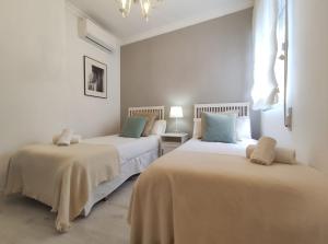 dwa łóżka w pokoju z białymi ścianami w obiekcie Covadonga Suite Home w Sewilli