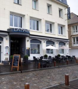 a restaurant with tables and chairs in front of a building at Le Grand Hôtel de la Marine in Port-en-Bessin-Huppain