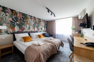 ザモシチにあるHotel Jubilatのベッドと壁画が備わるホテルルーム