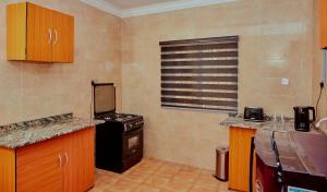 Il comprend une petite cuisine avec une cuisinière et une fenêtre. dans l'établissement Mainstream Shortlet Apartment Ltd, à Gbogije