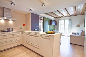 a large kitchen with white cabinets and a table at Ola Living Portaferrissa in Barcelona