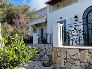 ein weißes Haus mit einem Tor und einer Steinmauer in der Unterkunft Villa Ampelaki 2 in Paleokastritsa
