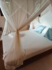 a bedroom with a white bed with a canopy at Alto Amor in Atins