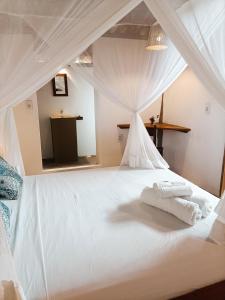 a white bed with white towels on top of it at Alto Amor in Atins
