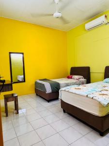 three beds in a room with yellow walls at MH Homestay No2 at Alor Setar in Alor Setar