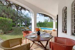 un patio con mesa, sillas y piscina en Casa da Oliveira, en Loulé