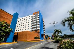 a large white building with blue columns next to a street at Lidotel Margarita in Pampatar