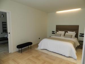 a white bedroom with a bed and a black stool at HOTEL MANEL in Martorell