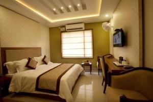 a bedroom with a bed and a desk and a window at Rotano Glitz Inn - Glitz Inn Calicut in Kozhikode