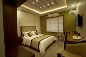 a bedroom with a bed and a window and a chair at Rotano Glitz Inn - Glitz Inn Calicut in Kozhikode