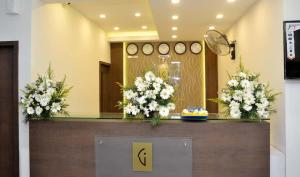 a reception desk with white flowers on top of it at Rotano Glitz Inn - Glitz Inn Calicut in Kozhikode