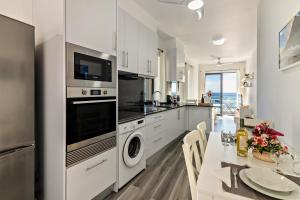 uma cozinha com armários brancos e uma mesa com uma sala de jantar em Casa Homem do Mar em Paul do Mar