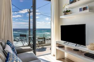 a living room with a television and a view of the ocean at Casa Homem do Mar in Paul do Mar